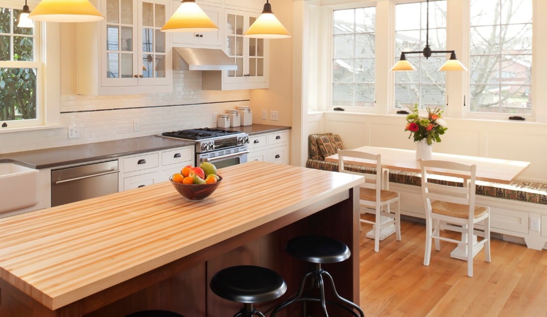 Bright kitchen with a butcher-block island, white cabinetry, and a window-side dining nook.