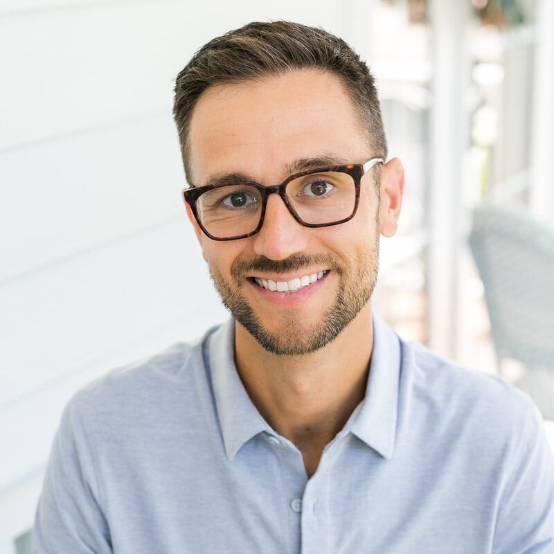 Ryan Berry, a real estate agent from Insiders Realty, with glasses and a blue shirt, is smiling.