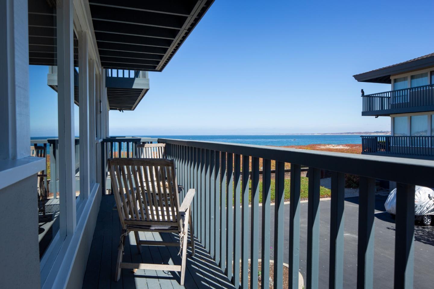 Balcony with a wooden chair overlooking the ocean and coastline.