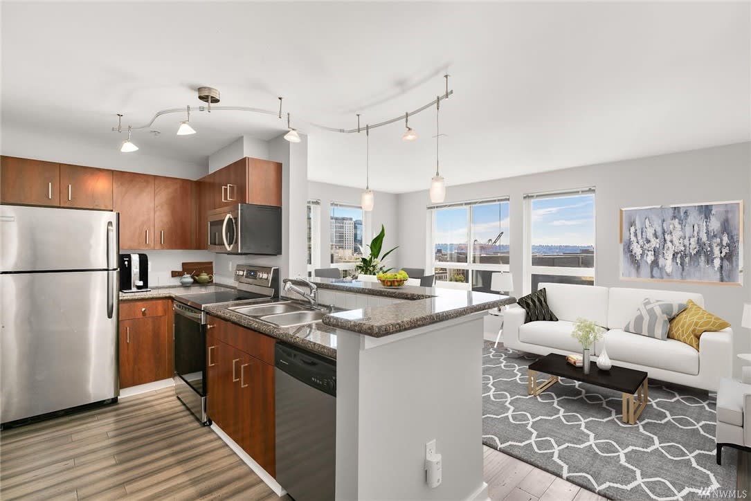 A luxurious, open-concept kitchen and living room in a modern home with gleaming hardwood floors.