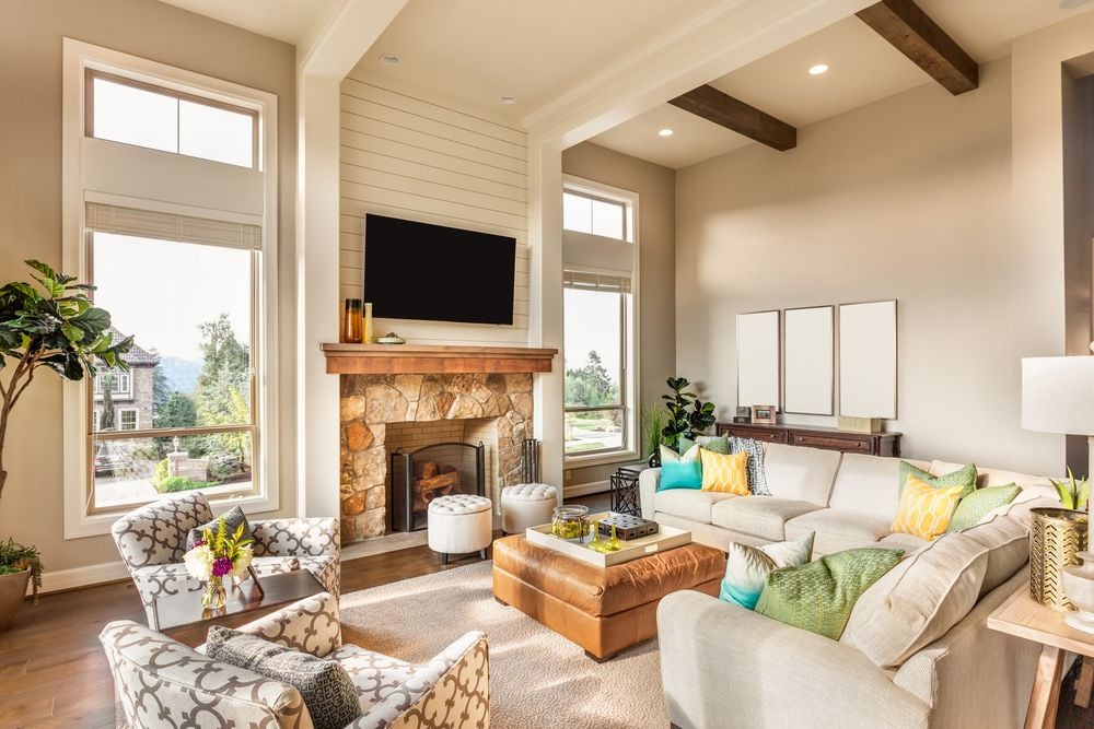 Living room with a stone fireplace, exposed ceiling beams, and a large sectional sofa.