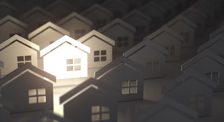 A row of white houses in shadow, creating a pattern with the roofs and windows, representing a community or housing development.