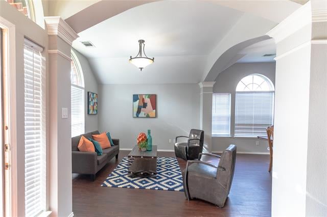 Living room with gray seating, a blue geometric rug, and arched windows beneath a vaulted ceiling.