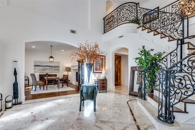 Foyer with a marble floor, ornate wrought-iron staircase, and dining room beyond.