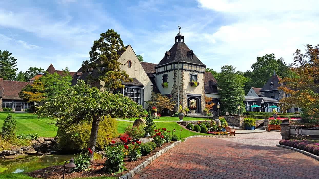 Tudor style development with green manicured landscape and green umbrellas over tables