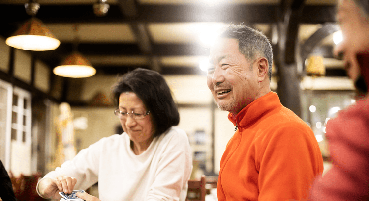 A photo of two smiling people, one male and one female, appearing to be in a casual, friendly setting, possibly a café or restaurant.