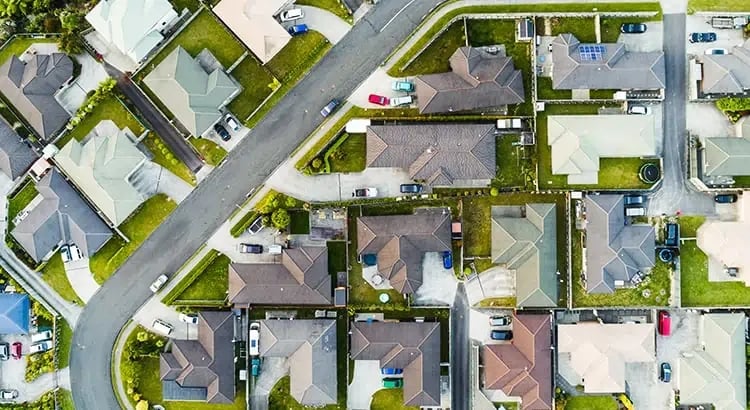 An aerial view of a suburban neighborhood with houses, streets, and lawns.