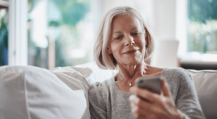 A photo of an elderly woman sitting comfortably and using a mobile phone, suggesting topics related to technology use among seniors or lifestyle.