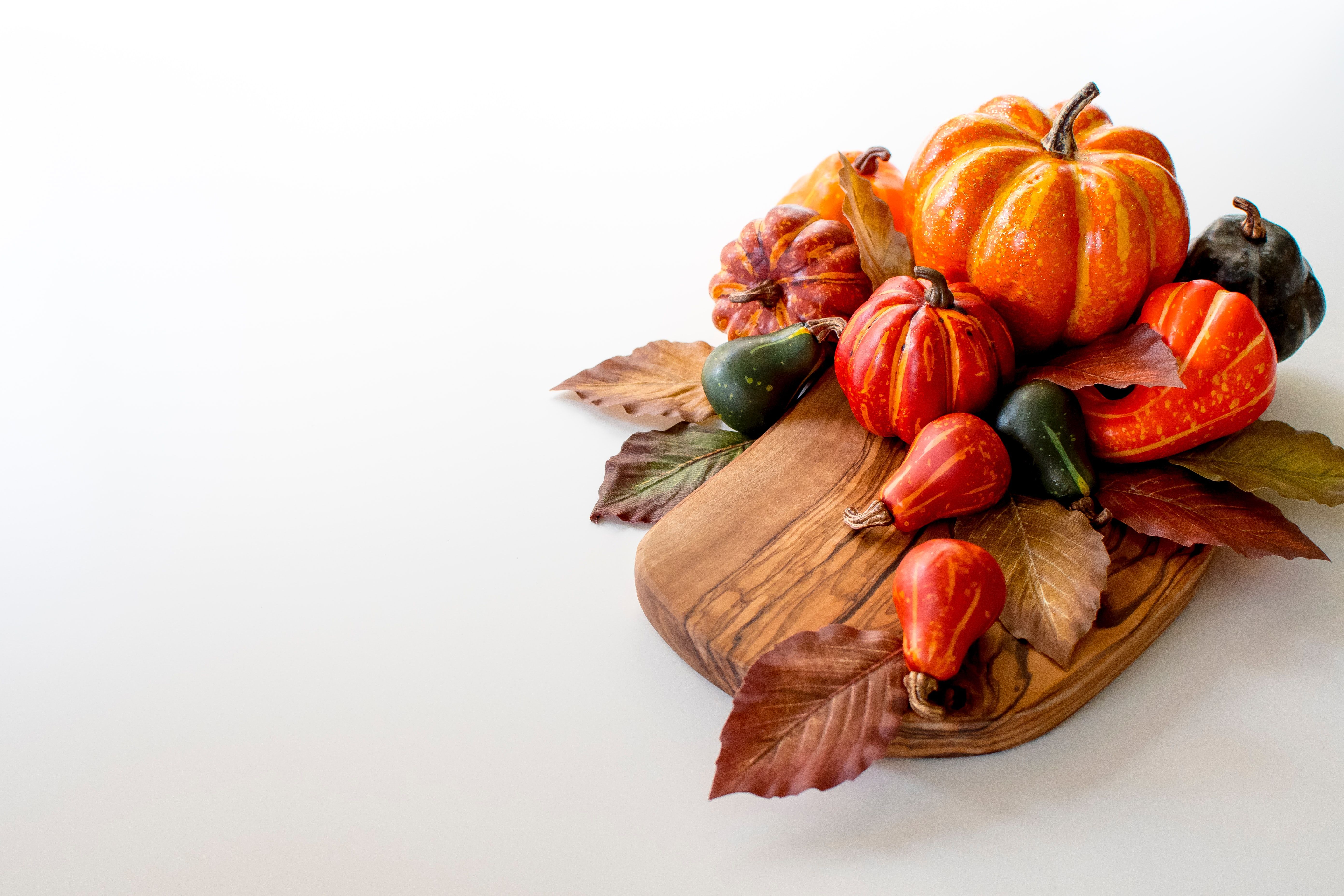 Autumn pumpkins and gourds arranged with dried leaves on a wooden board.