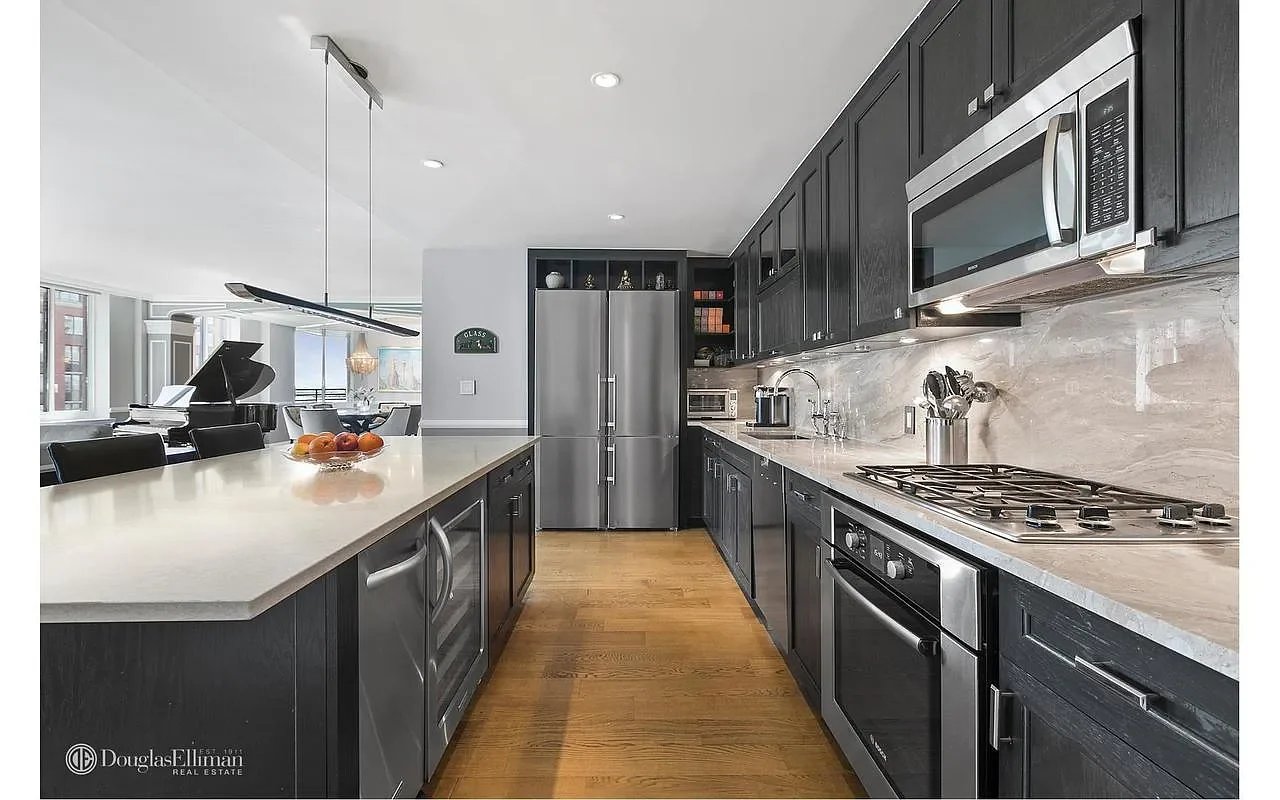 Open-plan kitchen with dark cabinets, stone counters, stainless appliances, and a large island.