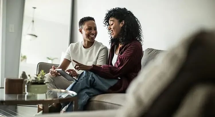 A couple sitting on a couch, engaged in a pleasant conversation. The setting appears to be casual and comfortable, indicating a relaxed home environment.