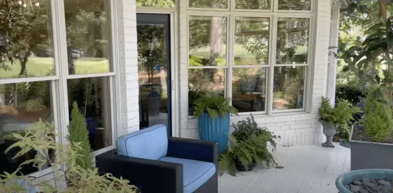 A serene porch adorned with elegant blue chairs and vibrant potted plants.