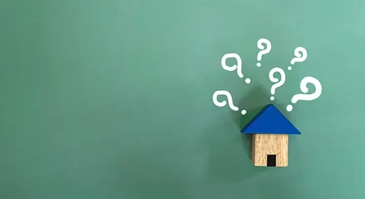 A small house model with question marks and arrows around it on a green background, representing questions or decisions related to housing.