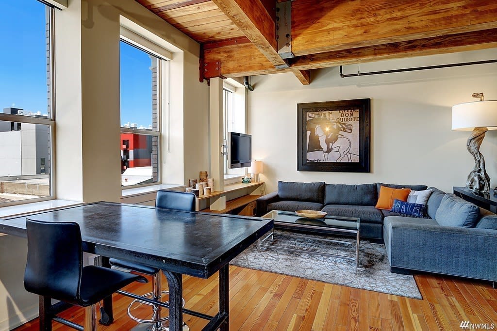 Chic condo with exposed beams, large windows, and modern decor, epitomizing upscale urban living.