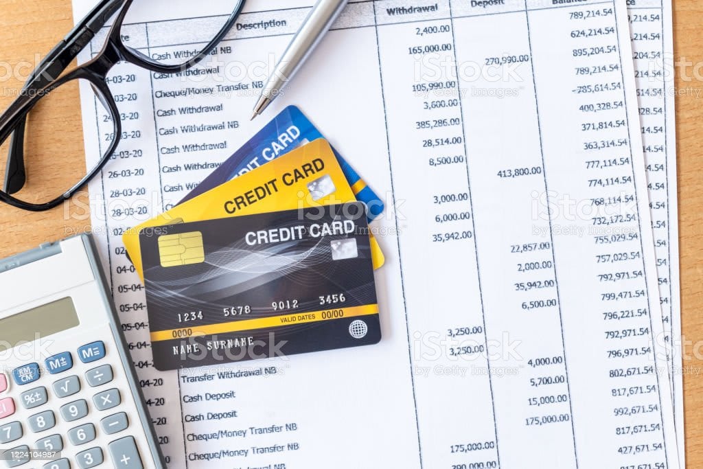 Bank statements with credit cards, eyeglasses and a calculator on top.