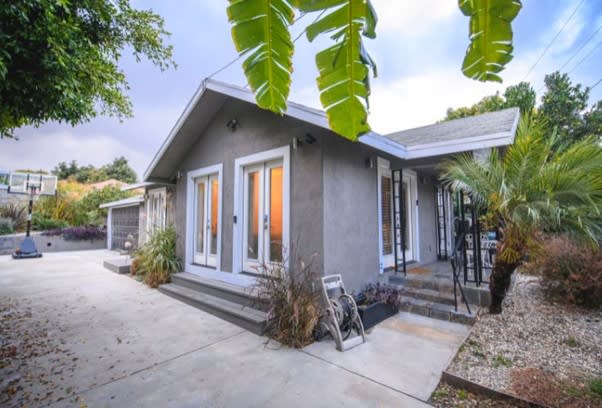 Los Angeles bungalo style home with a two car garage, basketball hoop and lush greenery surroundings