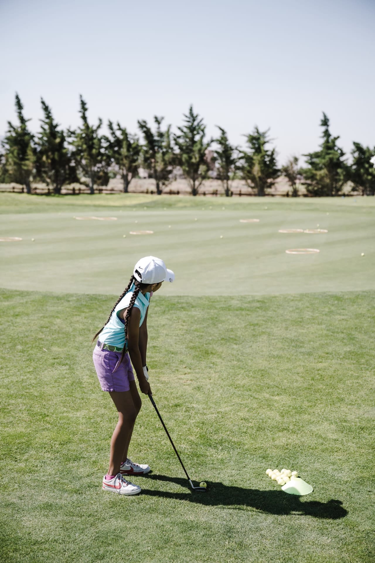 A young girl joyfully plays golf on a lush green field, creating a vibrant and energetic atmosphere.