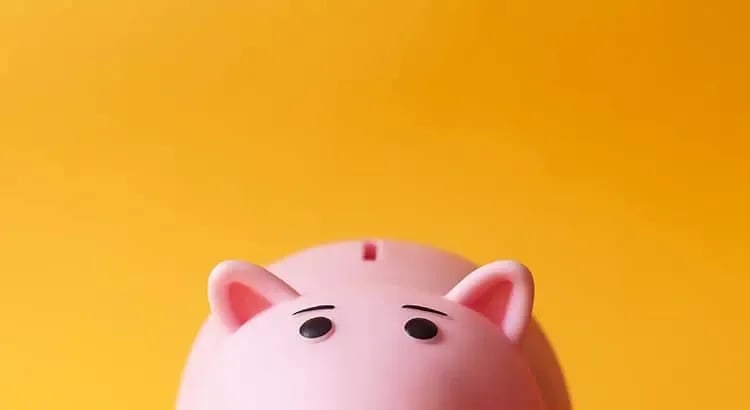 A pink piggy bank against a bright yellow background. This image symbolizes savings and financial management.