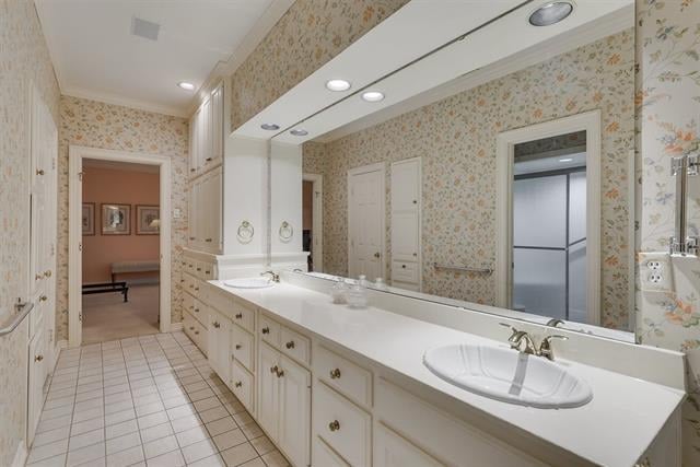 Bathroom with a long double-sink vanity, large mirror, and floral wallpaper.