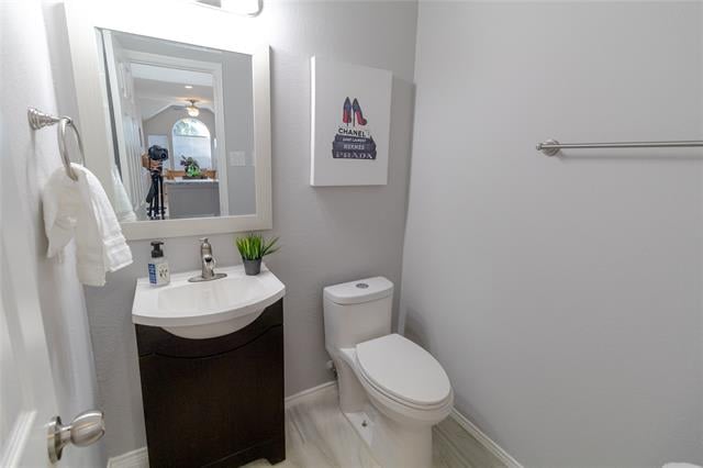 Bathroom with a dark wood vanity, curved white sink, toilet, and framed Chanel print.