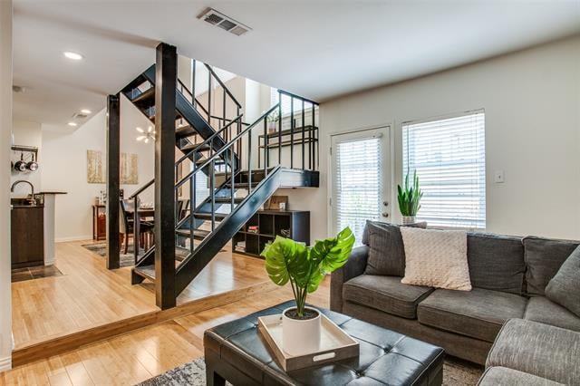Living room with gray sectional, potted monstera, and black metal open staircase.