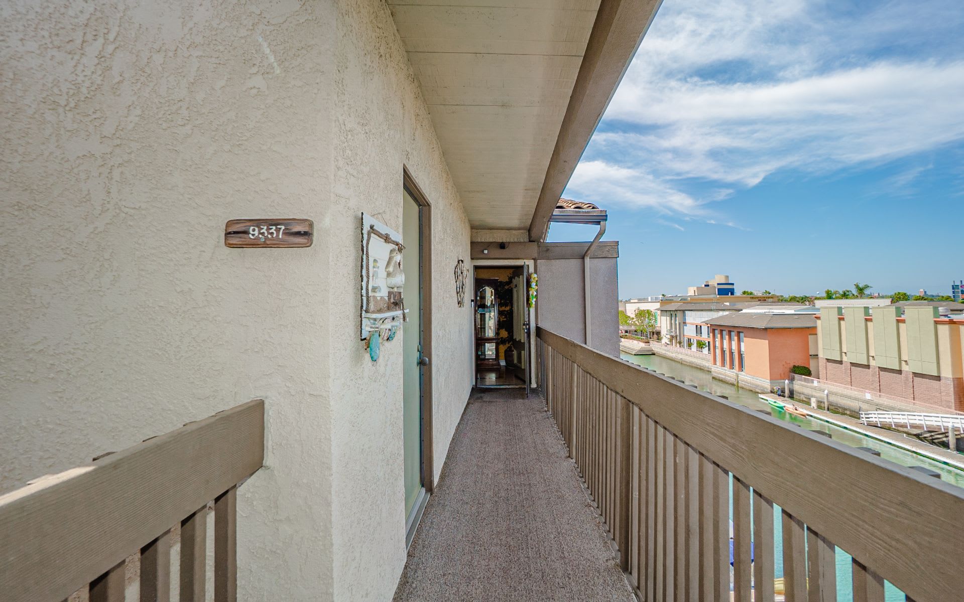 Covered apartment balcony overlooking a canal, with unit number 9337 on the stucco wall.