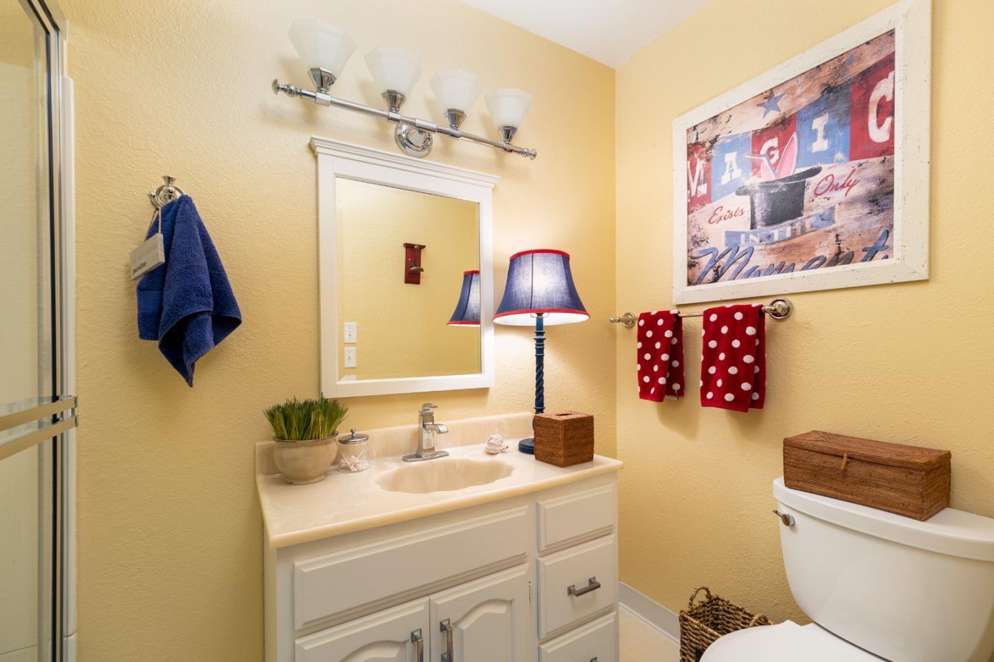 Bathroom with a white vanity, glass shower, and red polka-dot towels.