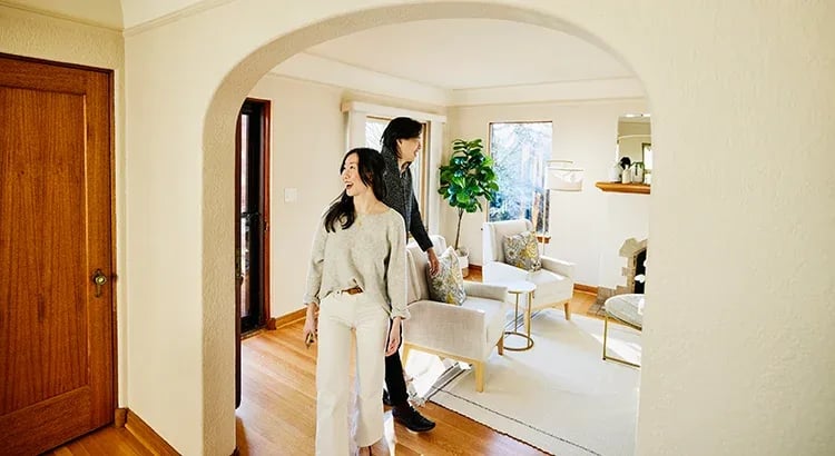 A couple walking through an archway into a nicely decorated home interior. The space looks elegant and welcoming.