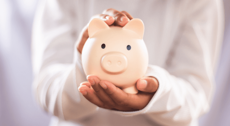 A person holding a pale pink piggy bank with both hands.