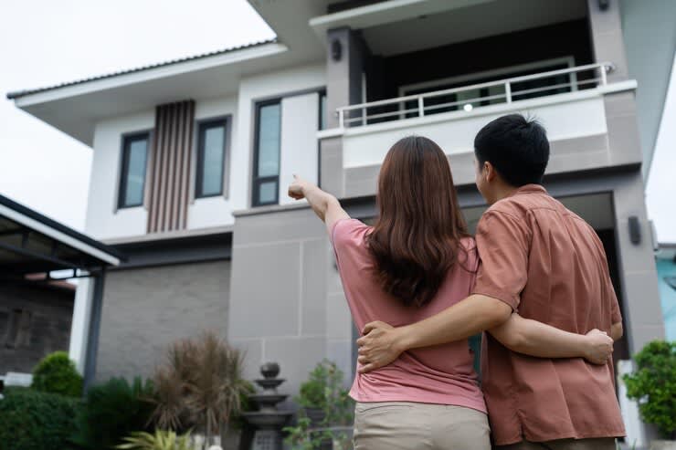 rear view couple standing outside a house