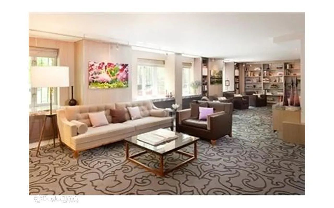 Furnished lounge with cream and brown sofas, a glass coffee table, and a large patterned carpet.