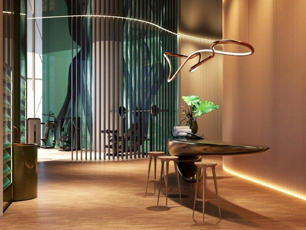 Bentley Residences interior with a sculptural reception desk and gym equipment behind a slatted partition.