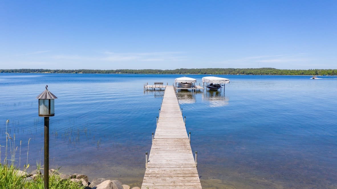 A tranquil scene of a wooden dock jutting out into a calm lake.