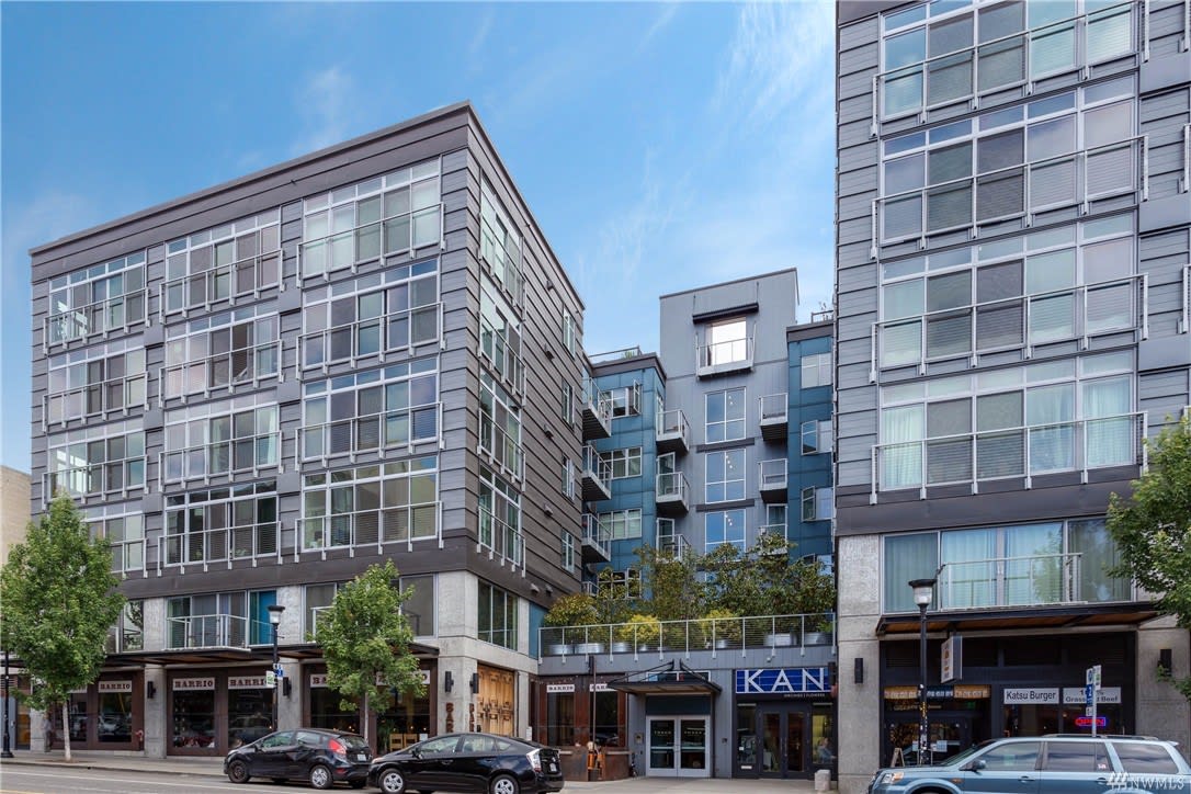 Modern condo complex with retail space on a lively street, showcasing contemporary urban living.