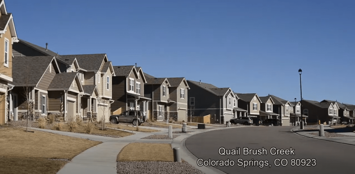 Quail Brush Creek neighborhood street lined with two-story homes and attached garages.