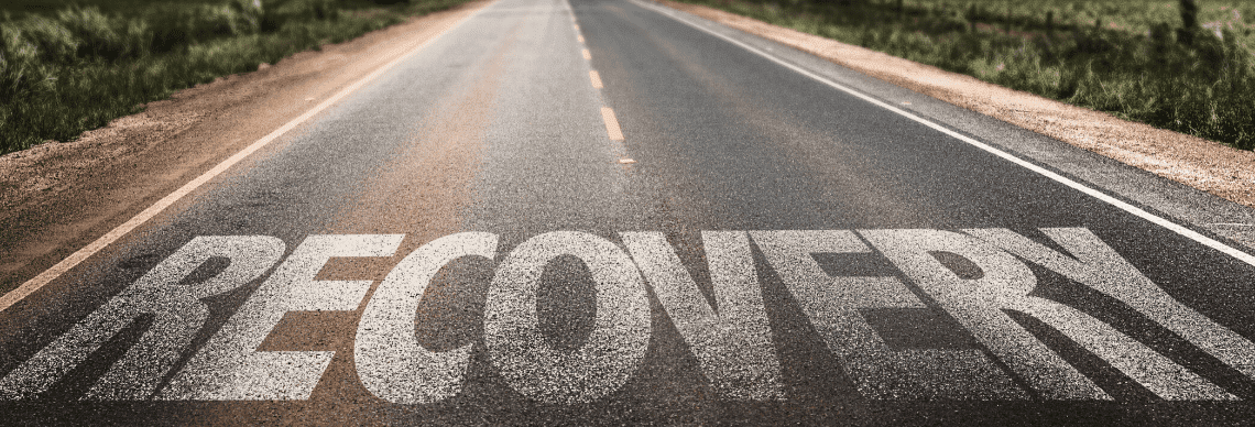 the word "RECOVERY" painted or overlaid on a long, open road, creating a powerful visual metaphor. 