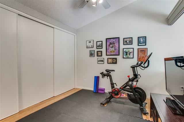 Home gym with a stationary bike, rubber flooring, framed artwork, and sliding closet doors.