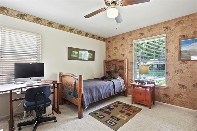 Bedroom with a wooden single bed, patterned wallpaper, and a desk beneath the window.