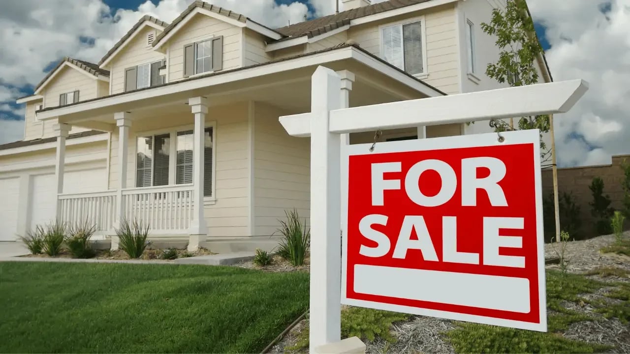 A house with a "For Sale" sign in the front yard, representing real estate listings and home buying.