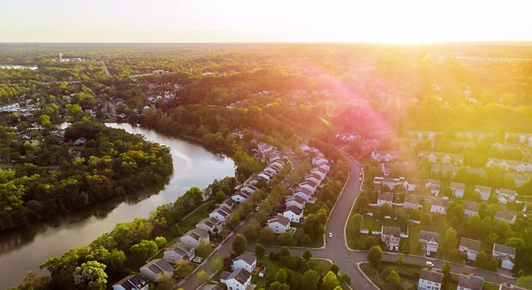 An aerial view of a residential neighborhood during sunset, with houses arranged along curving streets.