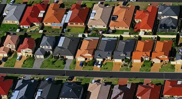 An aerial view of a suburban neighborhood with rows of houses, each with distinct colors and styles. This image emphasizes community, real estate, or urban planning.