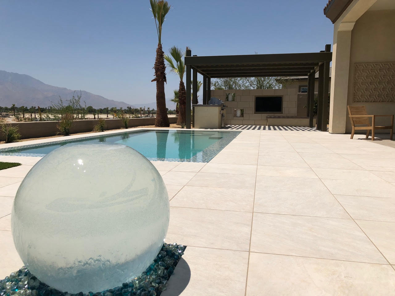 Resort style residential swimming pool patio area surrounded by palm trees