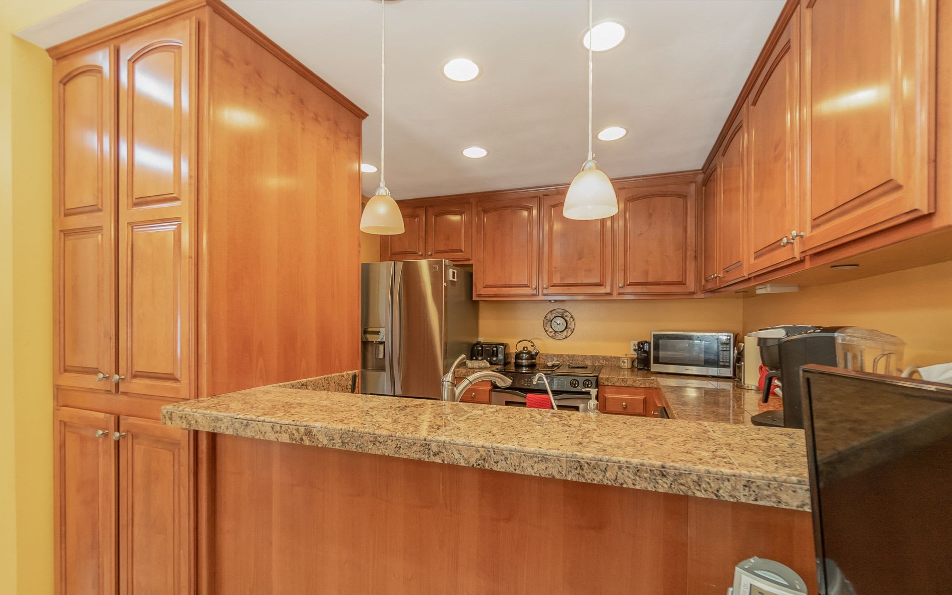 Kitchen with wood cabinets, granite breakfast bar, and stainless steel appliances.