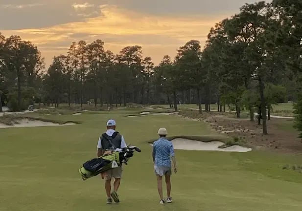 Two men strolling on a golf course at sunset, creating a serene and picturesque atmosphere.