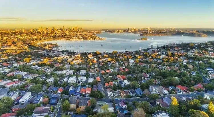 An aerial view of a coastal city with colorful rooftops and a waterfront. The image showcases urban planning and the beauty of a coastal town.