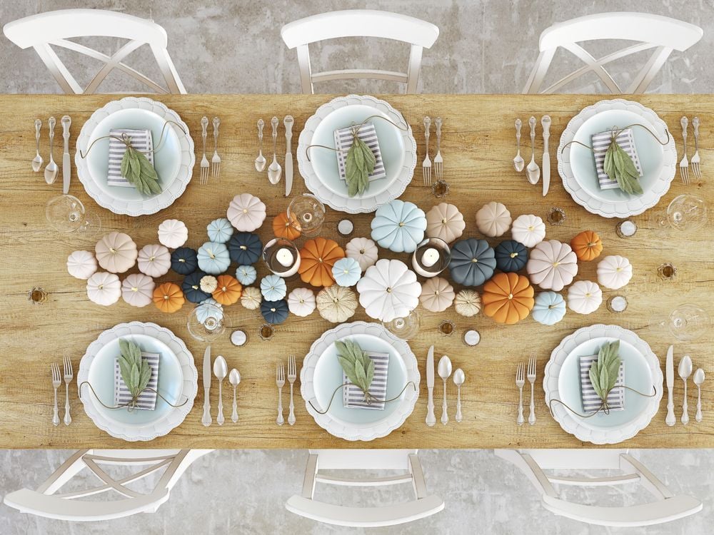 Autumn dining table set for six with a colorful pumpkin and gourd centerpiece.