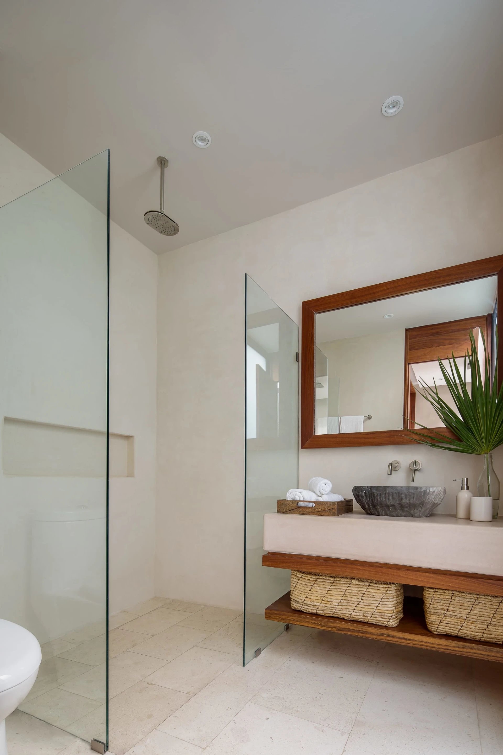 Modern bathroom with a glass walk-in shower and floating wood vanity with a dark vessel sink.