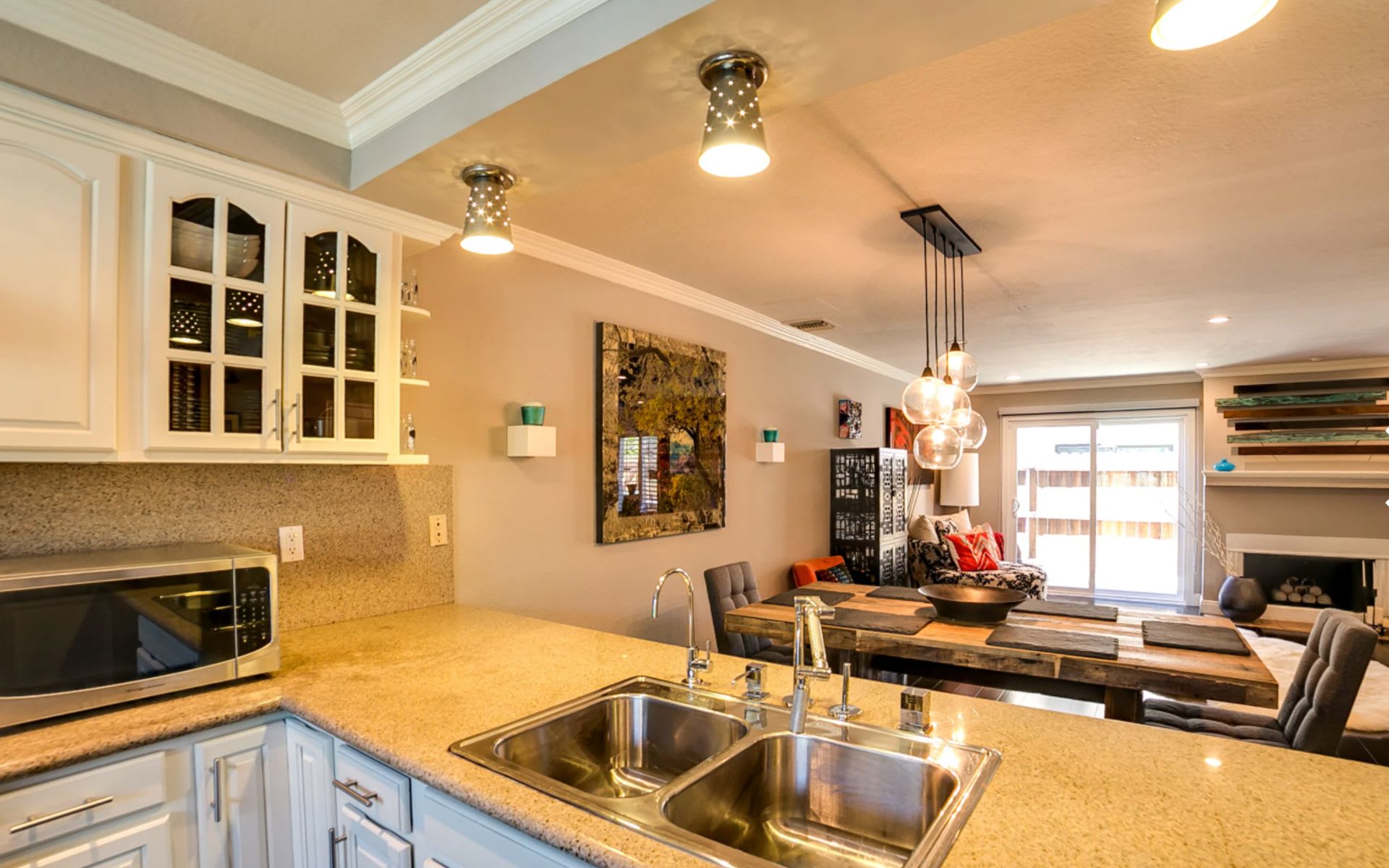 Open-plan kitchen with granite counters, double sink, and a rustic wood dining table.