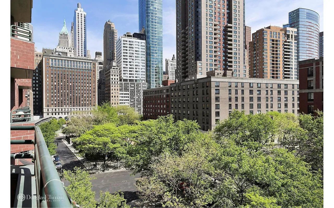City skyline and leafy park viewed from a balcony.