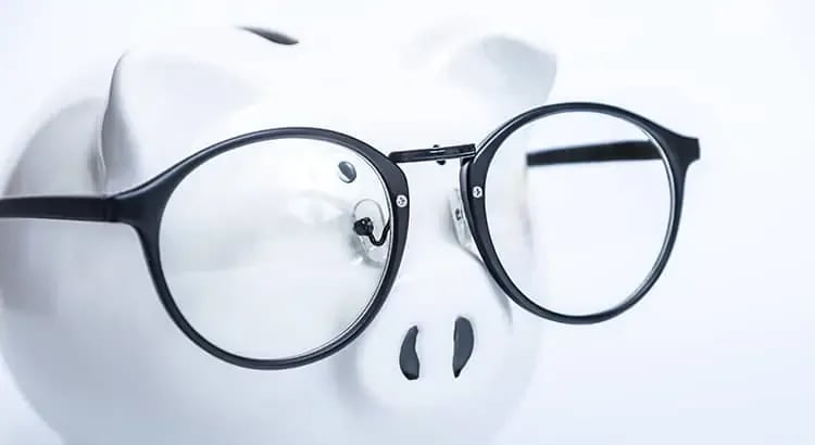 A white piggy bank wearing black glasses, suggesting financial savings or smart money management.